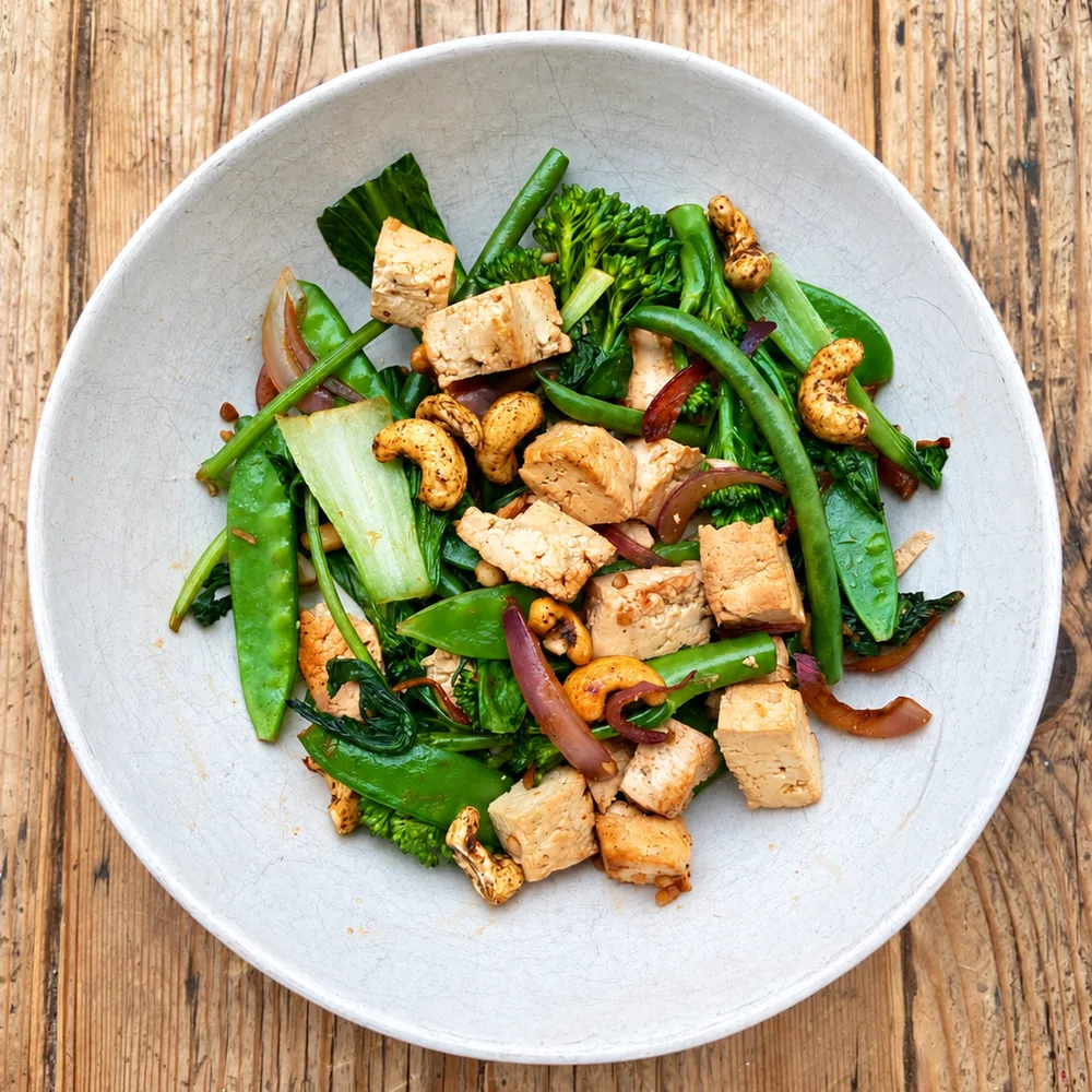 Bowl of tofu stir-fry with tenderstem broccoli, green beans, mangetout, pak choi and cashews