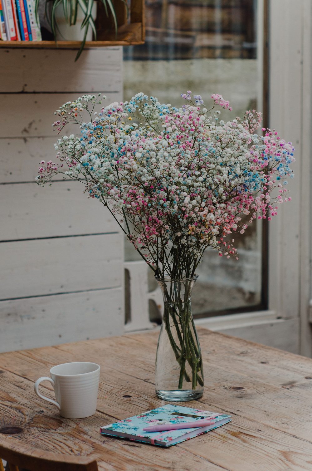 A vase of flowers on a table with a notebook